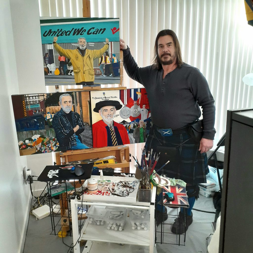 Glenn Hesse posing with his paintings at his art studio. 